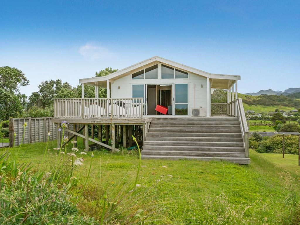 Cette petite maison blanche dispose d'une terrasse couverte et d'escaliers. dans l'établissement Ocean Beach Beauty - Tairua Holiday Home, à Tairua