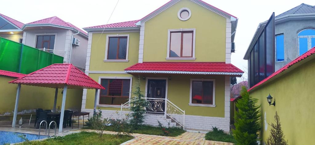 uma casa amarela com um telhado vermelho em Guest house in Qabala em Gabala