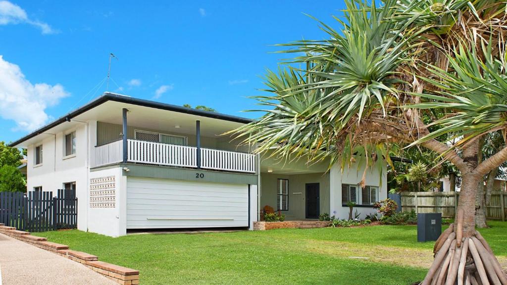 a white house with a fence and a palm tree at 20 Mackay St Dicky Beach QLD in Caloundra