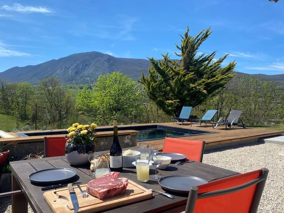 una mesa con platos de comida y una botella de vino en Balcons du Royans.Logement entier Piscine, en Saint-Jean-en-Royans