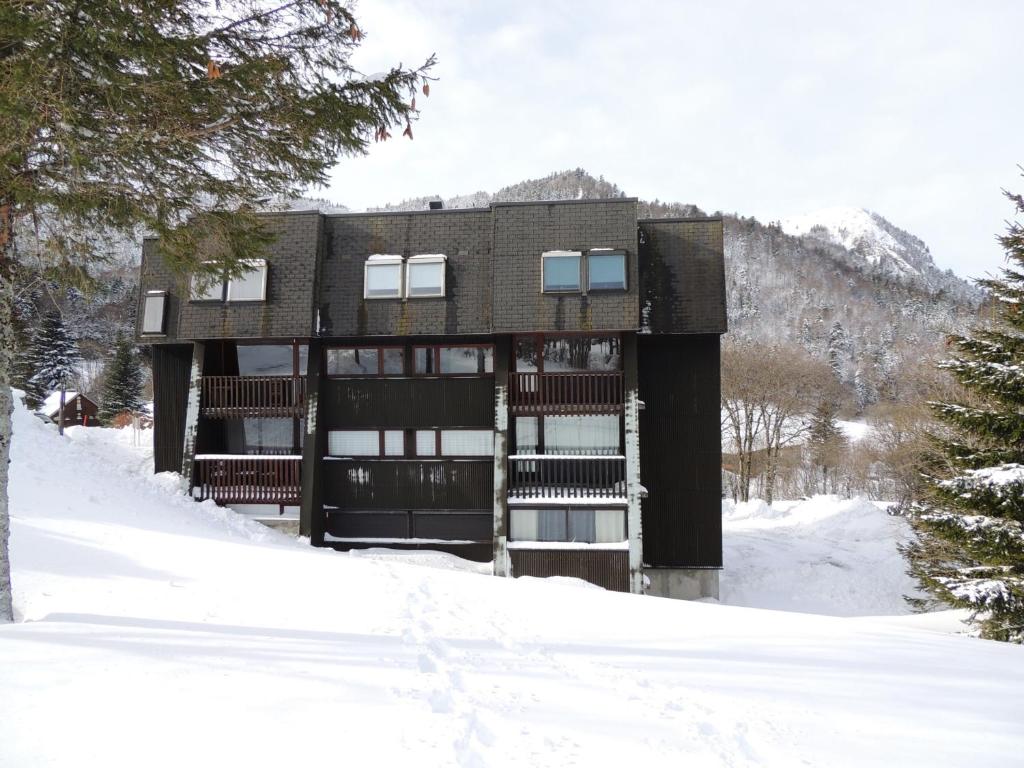 un edificio en la nieve frente a una montaña en Appartement Mont-Dore, 2 pièces, 4 personnes - FR-1-415-92, en Le Mont-Dore