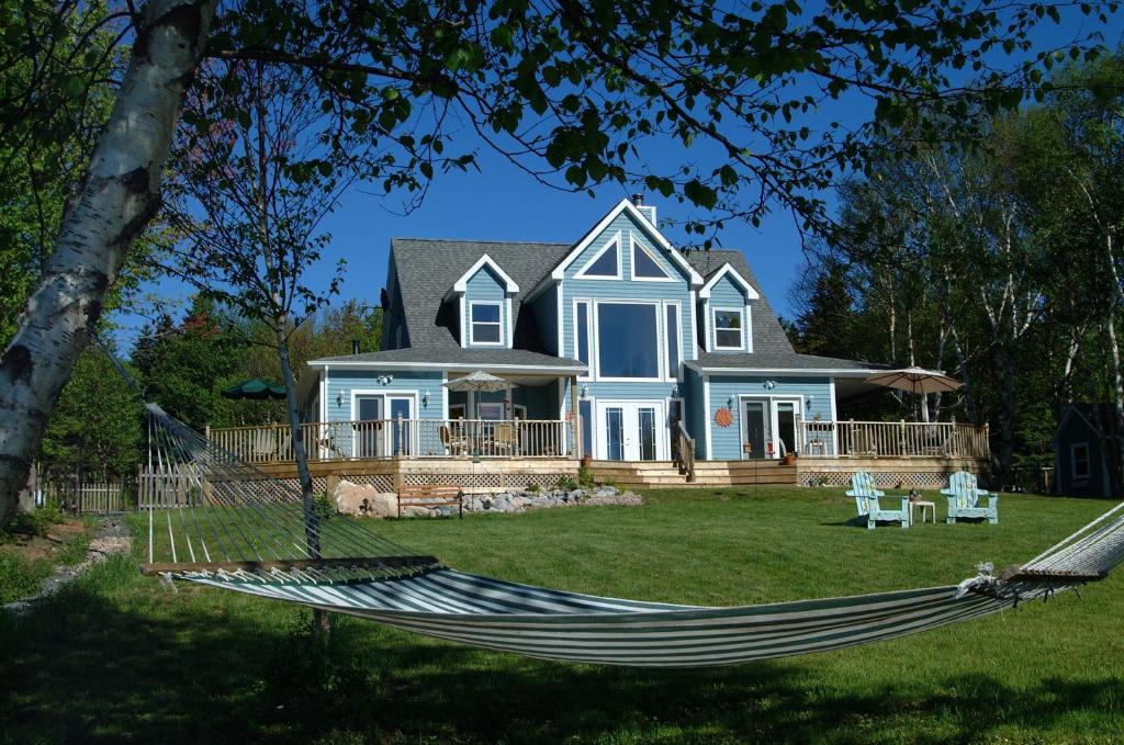 a house with a hammock in the yard at Sea Parrot Ocean View Manor in Indian Brook