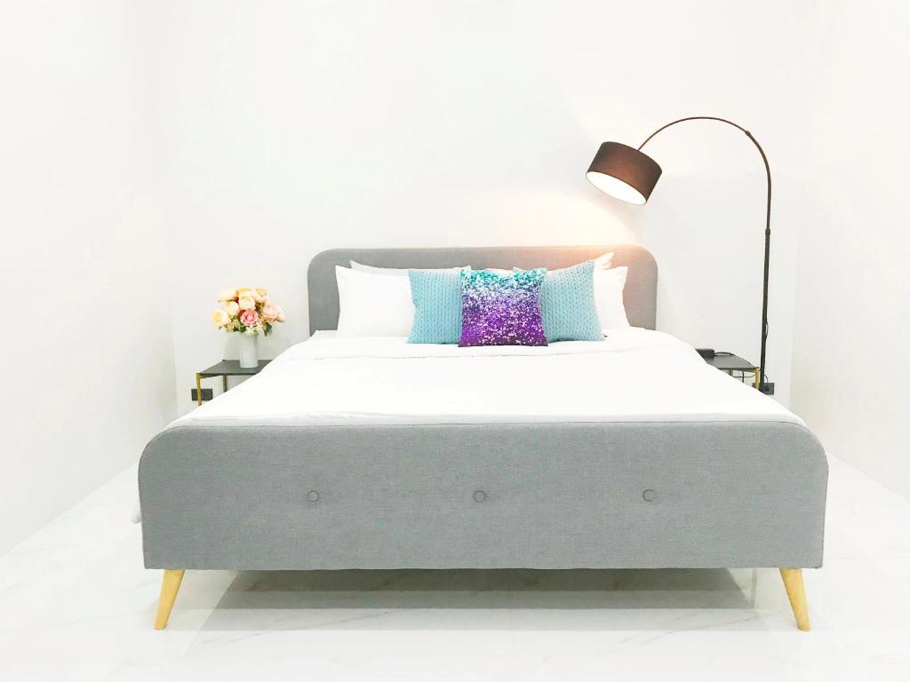 a white bedroom with a large bed with a lamp at MeeTHan House in Chiang Mai