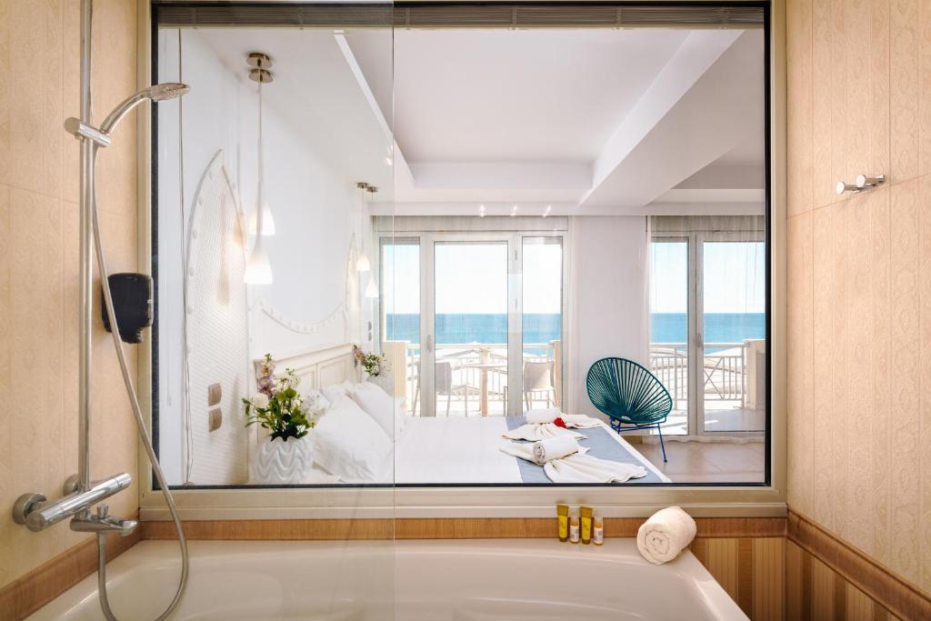 a bathroom with a tub and a view of a room at Hydrele Beach Hotel & Village in Potokáki