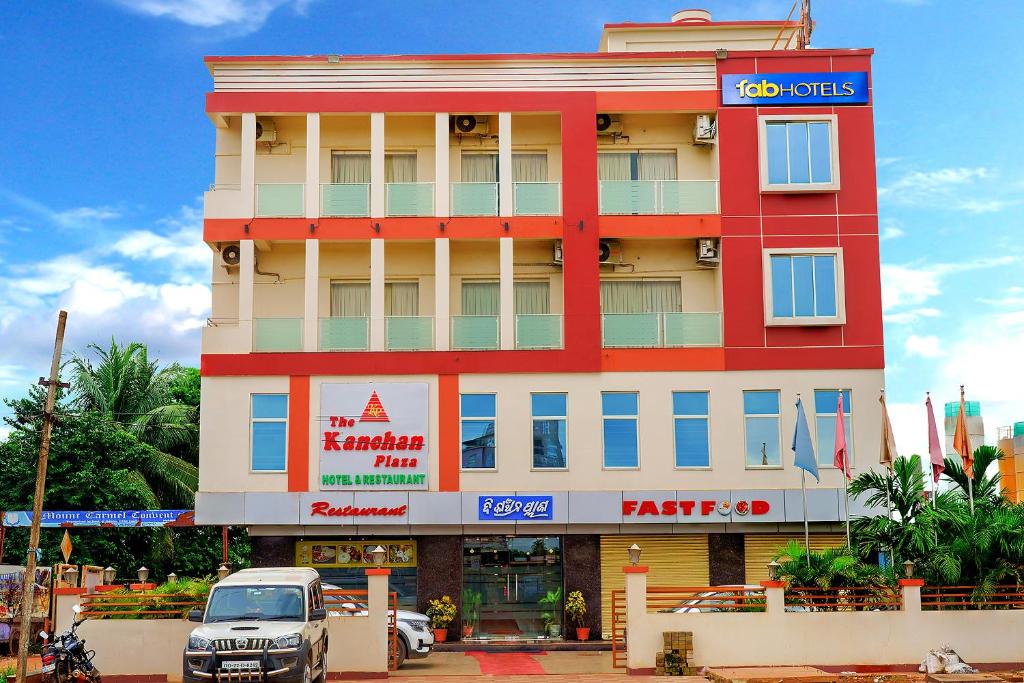 a red and white building with a car parked in front at FabHotel Kanchan Plaza in Bhubaneshwar