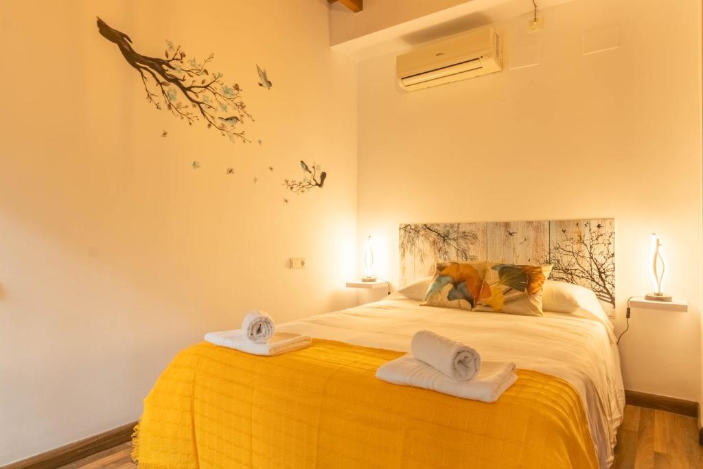 - une chambre avec un lit jaune et des serviettes dans l'établissement APARTAMENTO PATIO ANDALUZ EN SEVILLA, à Séville