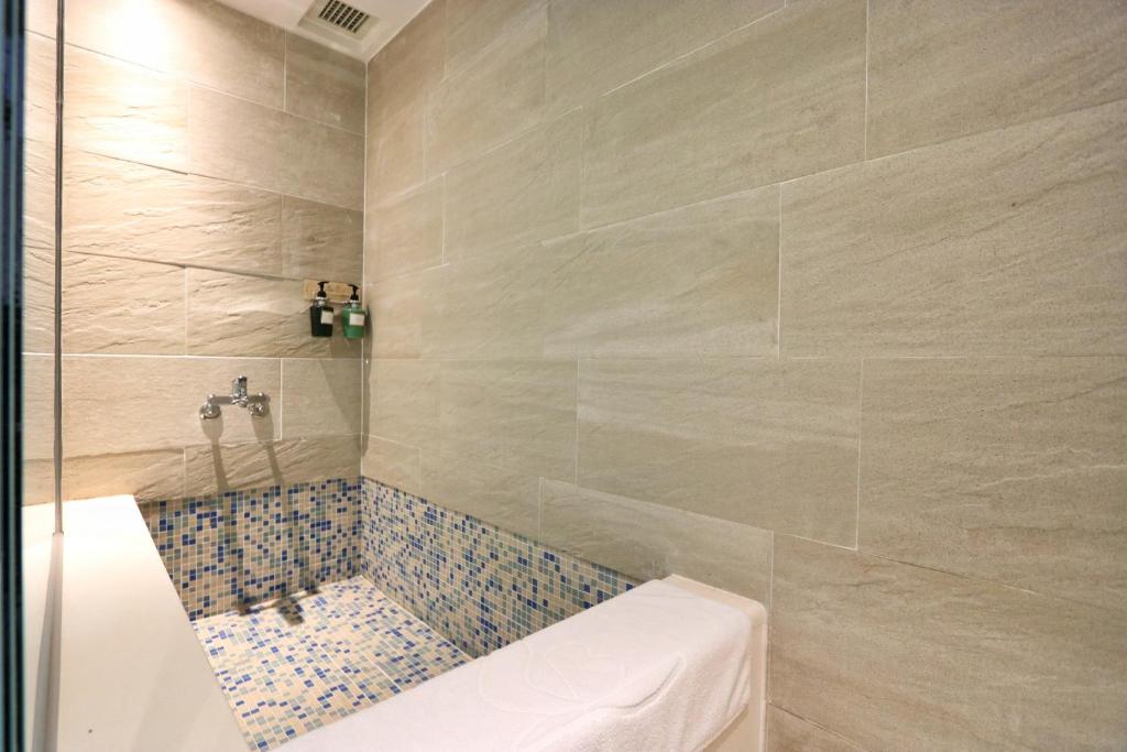 a bathroom with a shower with a toilet and tiles at Kenting Long Beach Hotel in Checheng