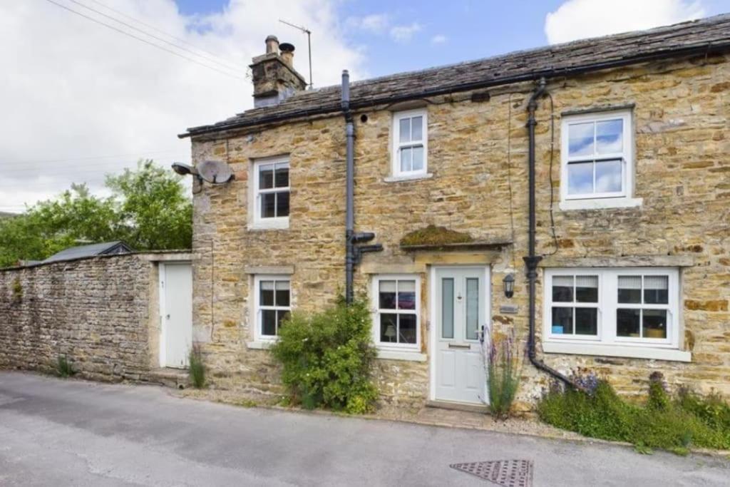 an old brick house with white doors and windows at Cringley Cottage in Askrigg