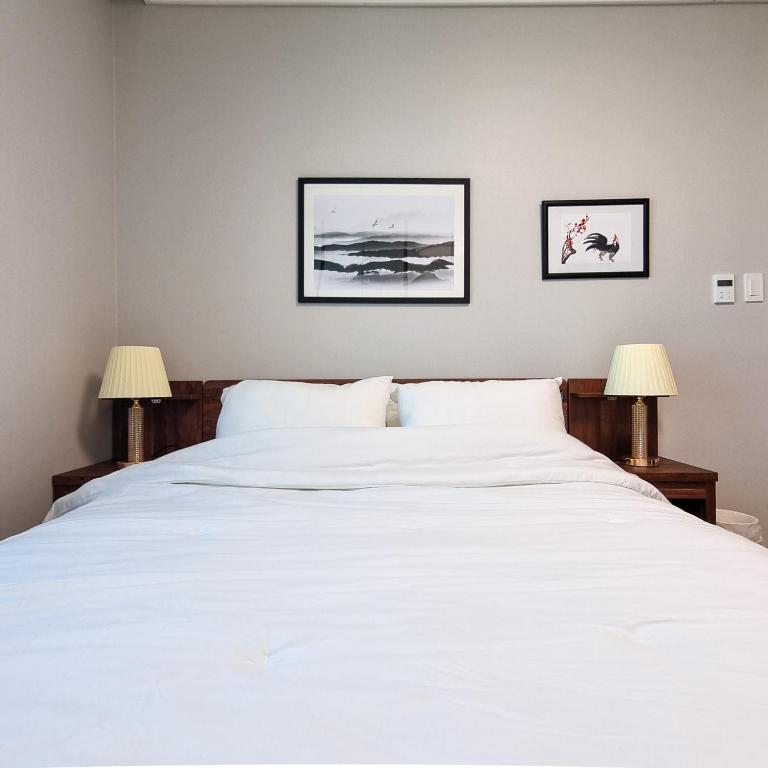 una camera da letto con un grande letto bianco con due lampade di Humphreys 2 min Vintage Korean Room a Pyeongtaek