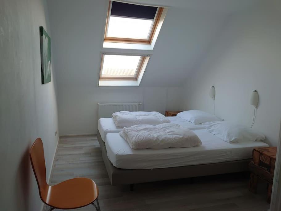 Un dormitorio con 2 camas y una silla. en De Oostkamer; Eiland appartement naast natuurgebied Boschplaat, en Oosterend