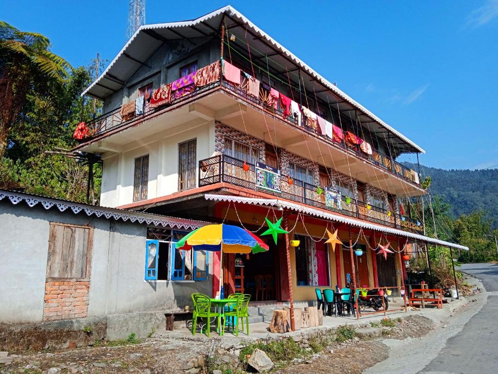 ein Gebäude mit Stühlen und einem Sonnenschirm davor in der Unterkunft Well Spring Homestay in Kalimpong
