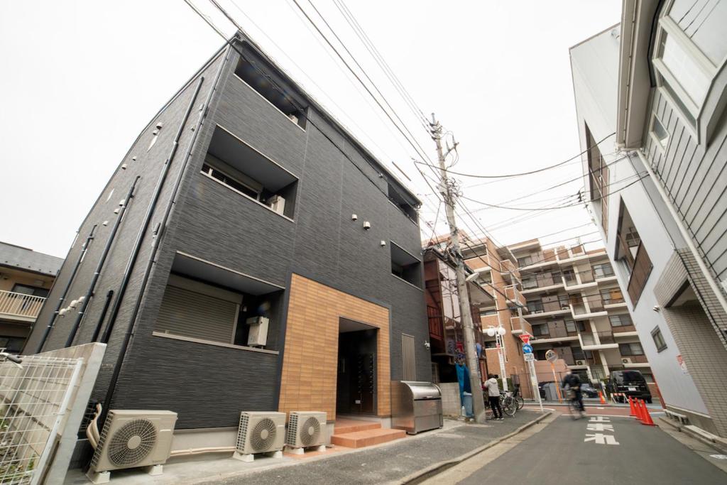 Un edificio nero sul lato di una strada di ミニマリズムホテル葛飾 a Tokyo