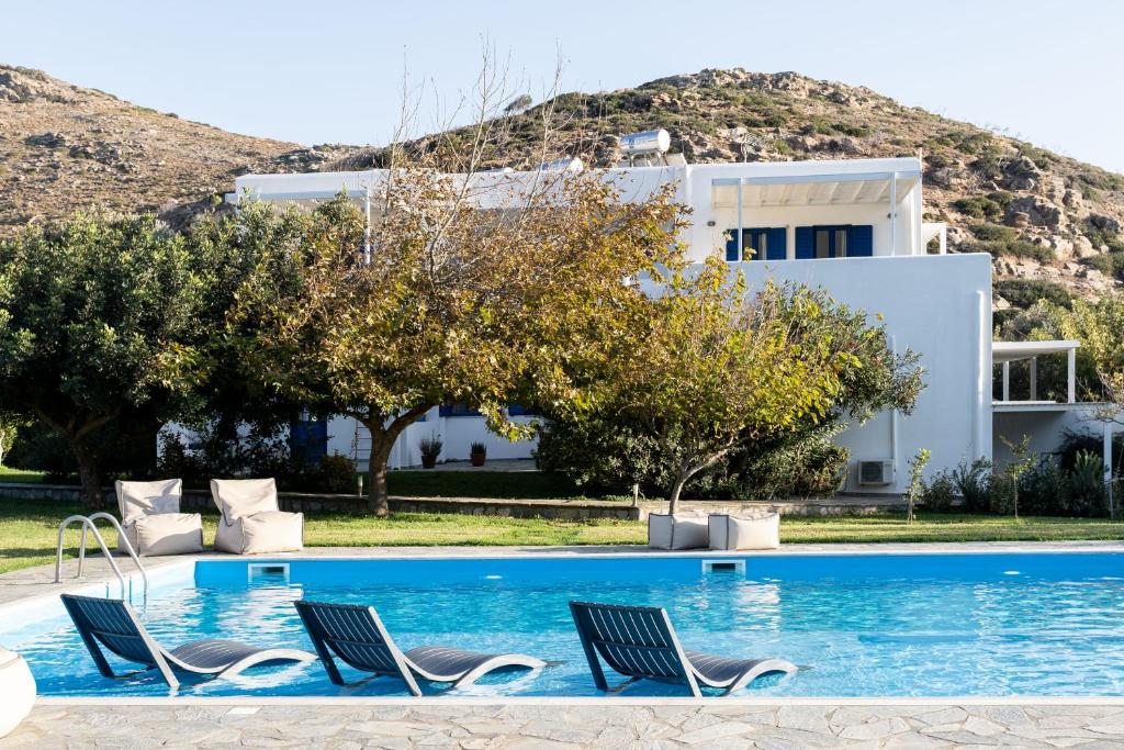 a pool with chairs and a house in the background at Alasthas in Gavrio