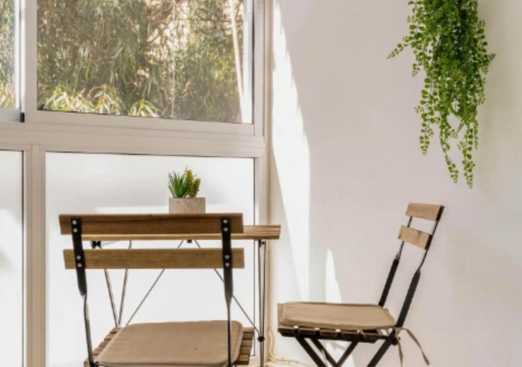 una mesa y una silla junto a una ventana en Central 1BR Oasis, Fast Fiber WiFi, Free Parking, Free Netflix with Shelter, en Haifa
