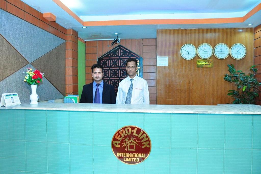 twee mannen achter een toonbank in een kamer bij Hotel Aero link Ltd in Dhaka