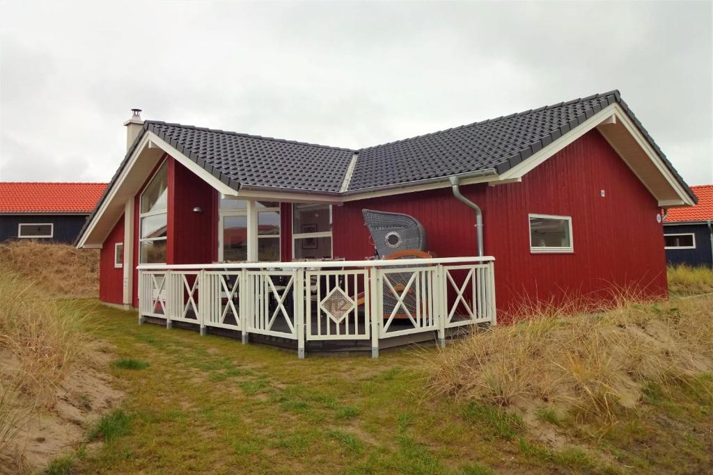 une maison rouge avec une terrasse blanche et une terrasse rouge dans l'établissement Resort 2 Sea Lodge C 112, à Großenbrode