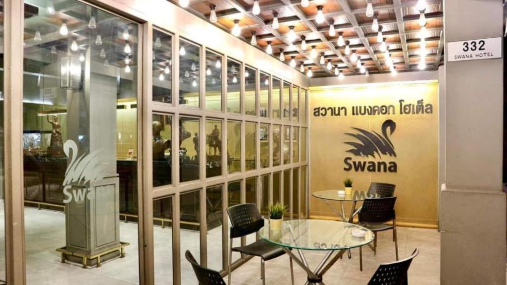 a room with a glass table and chairs in a building at Swana Bangkok Hotel in Bangkok
