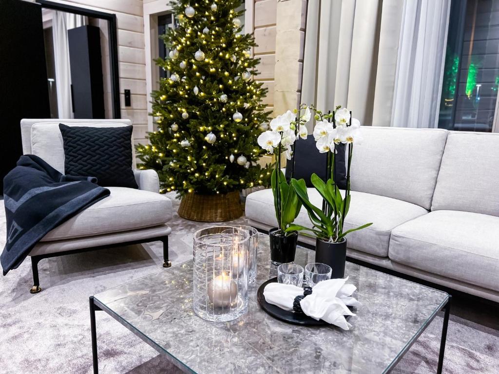 a living room with a white couch and a christmas tree at Santa's Luxury Boutique Villa - Santa Claus Village in Rovaniemi