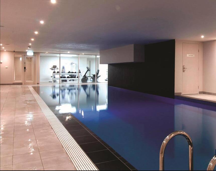a large swimming pool in a building with blue floors at Melbourne Luxury Penthouse in prime location in Melbourne