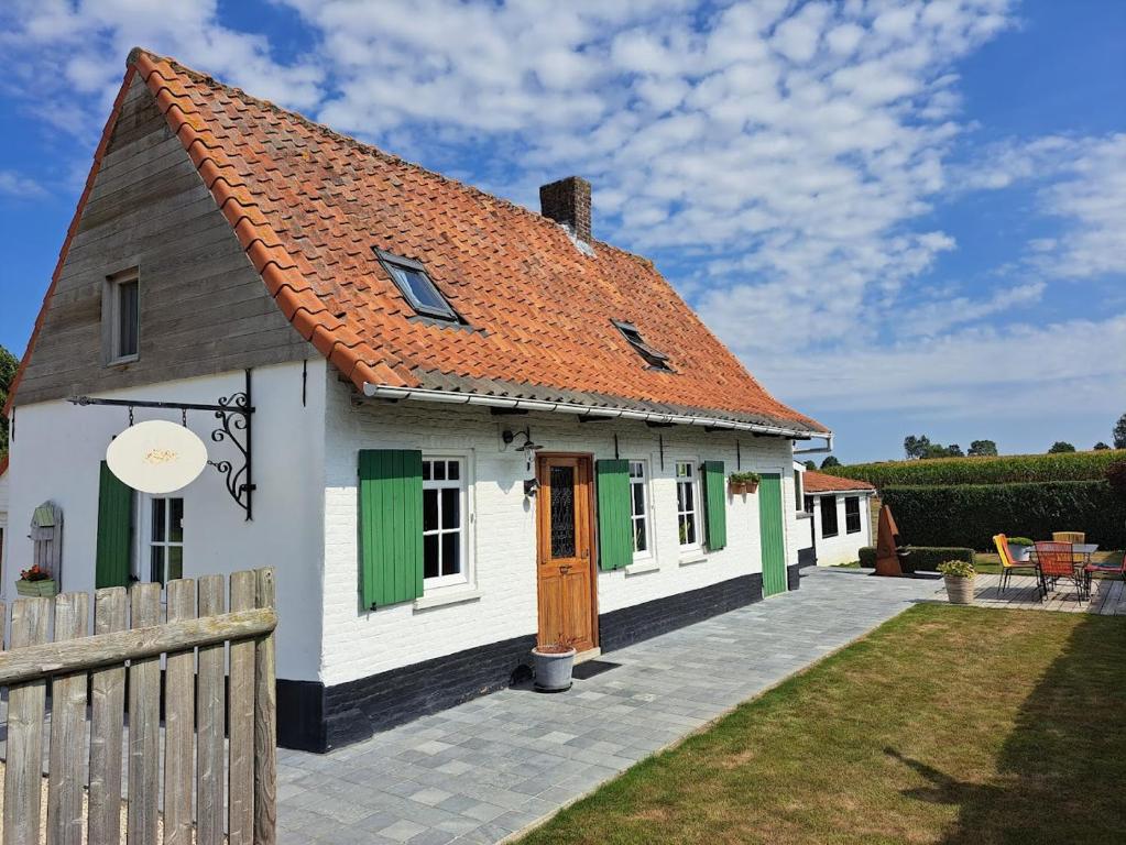 una pequeña casa blanca con techo naranja en 't Haringehuys en Poperinge