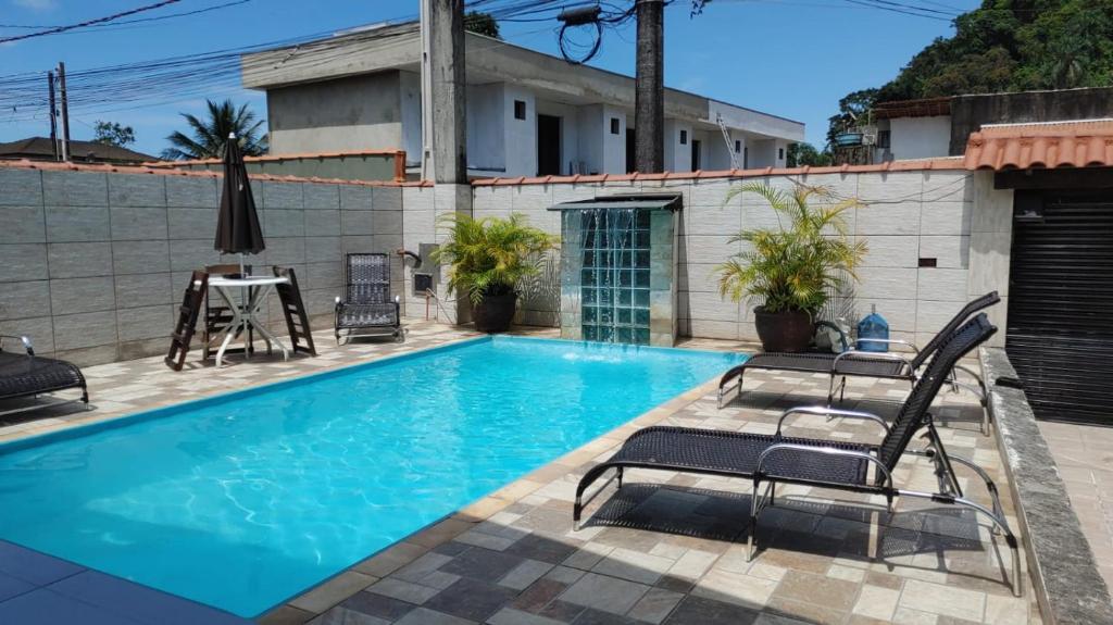 a swimming pool with two chairs and a table at Toca do Capitao in Boicucanga