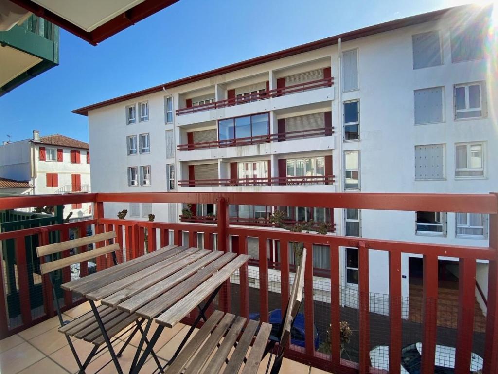 - un balcon avec un banc en bois et un bâtiment dans l'établissement Appartement Saint-Jean-de-Luz, 3 pièces, 6 personnes - FR-1-239-497, à Saint-Jean-de-Luz