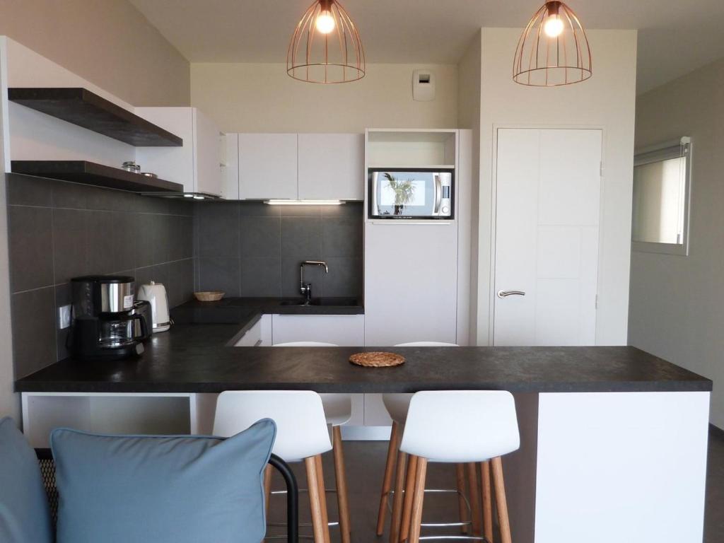 a kitchen with a black counter top and white cabinets at Appartement La Tranche-sur-Mer, 2 pièces, 4 personnes - FR-1-194-218 in La Tranche-sur-Mer