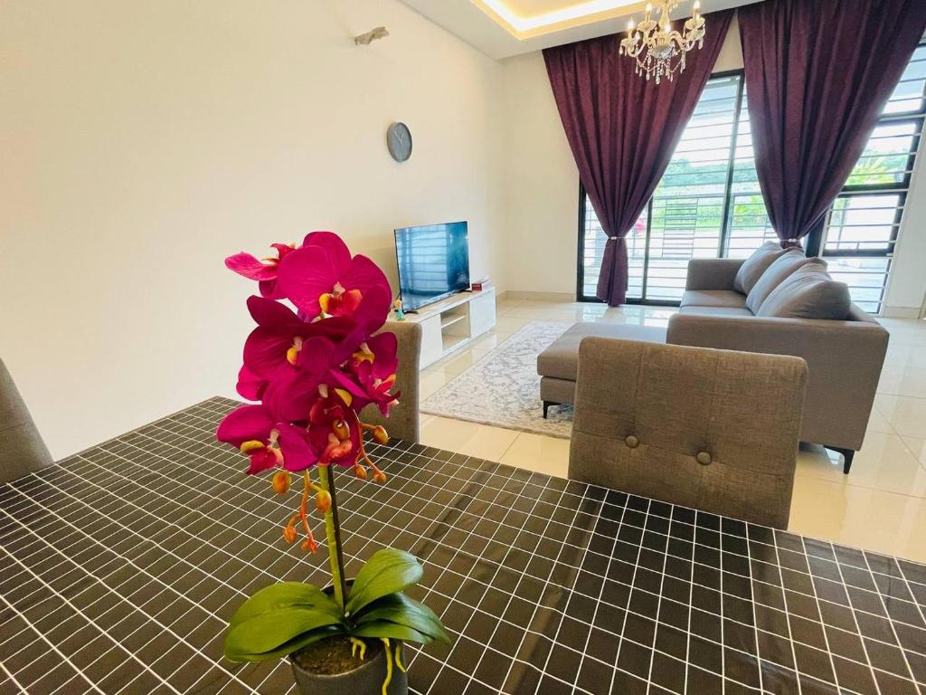 uma sala de estar com uma mesa com uma flor em Homestay 3BR near Setia Alam em Shah Alam