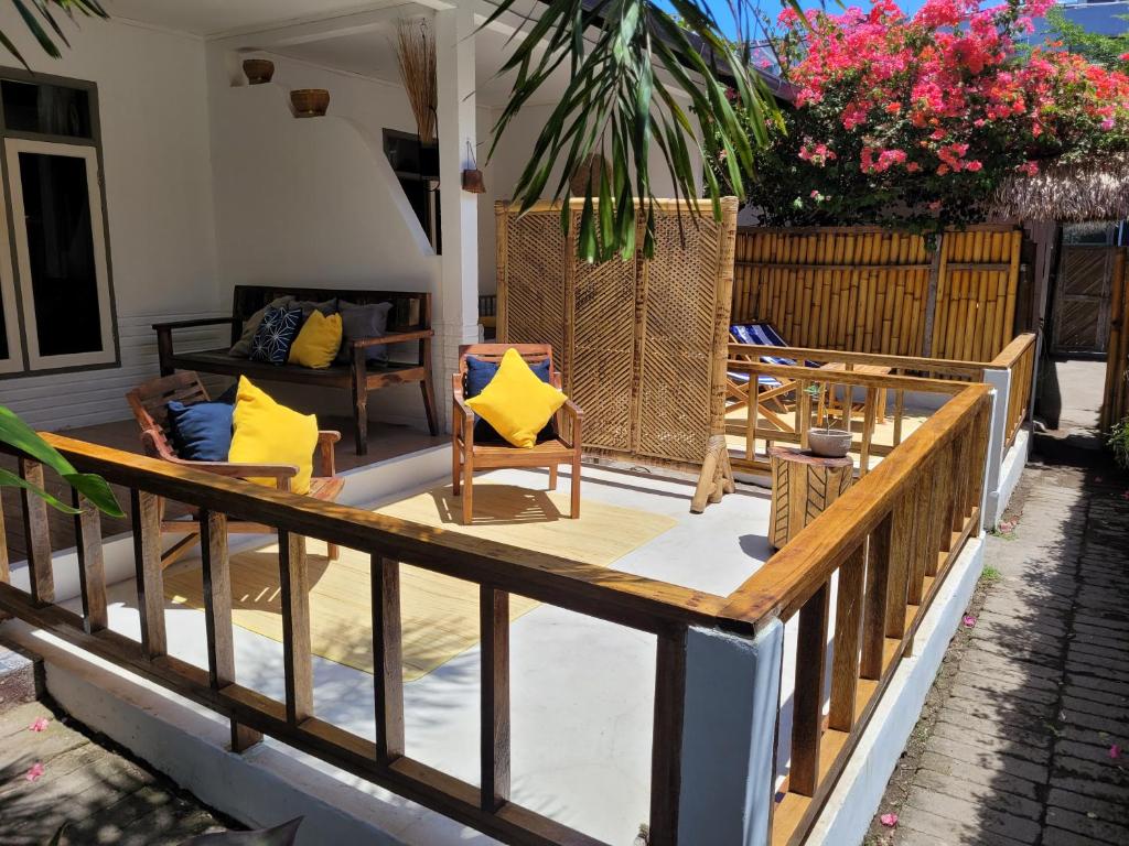 una terraza con sillas y mesas en una casa en The Crafty Rooms en Gili Air