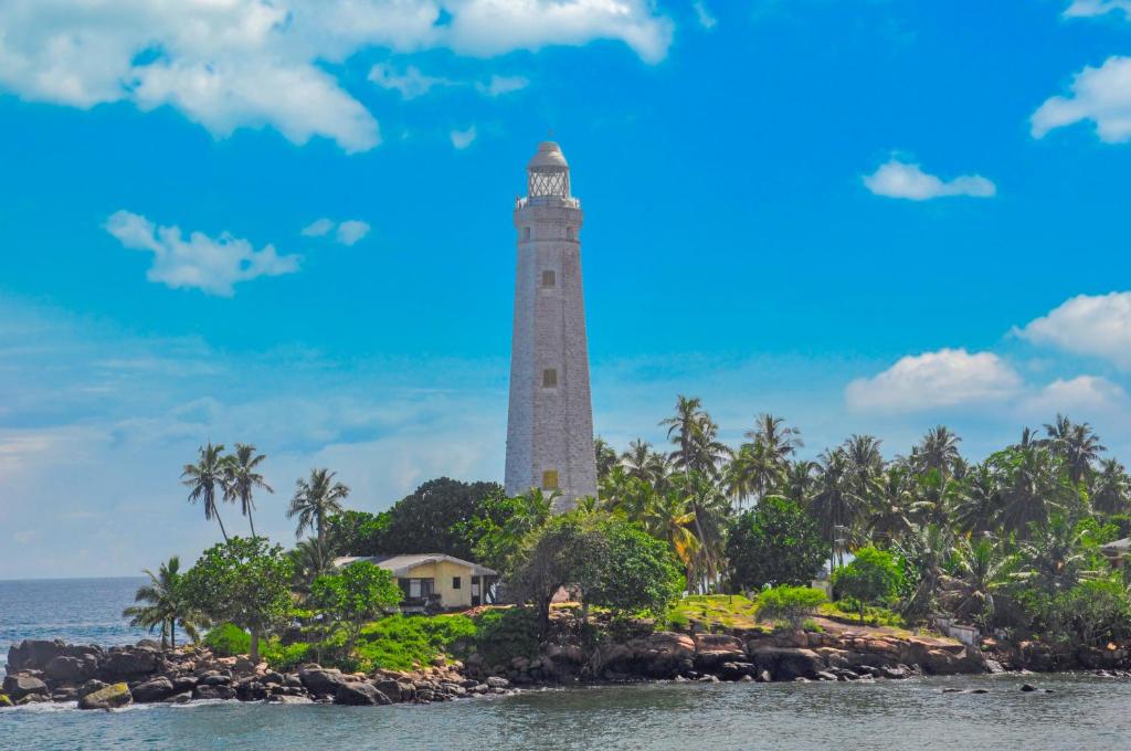 a lighthouse on a island in front of the ocean at Himashi Sea View Homestay in Gandara East