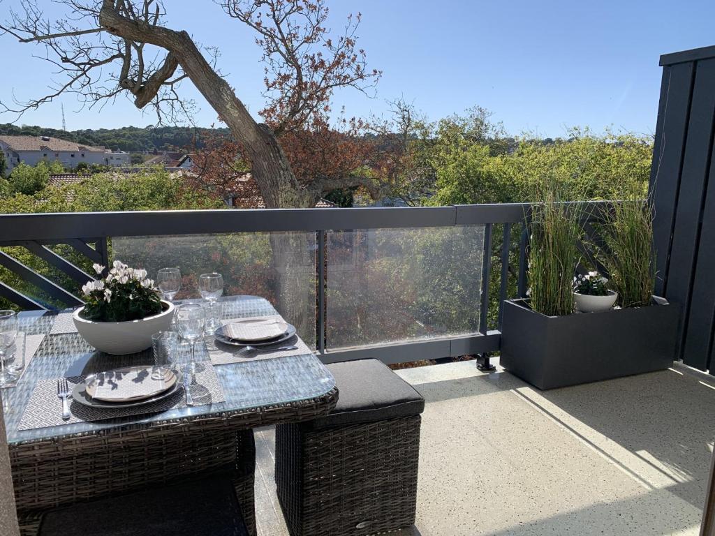 une table avec des assiettes et des verres sur un balcon dans l'établissement Magnifique T2 Duplex à Arcachon avec Terrasse, WiFi, à 100m de la Plage - FR-1-374-160, à Arcachon