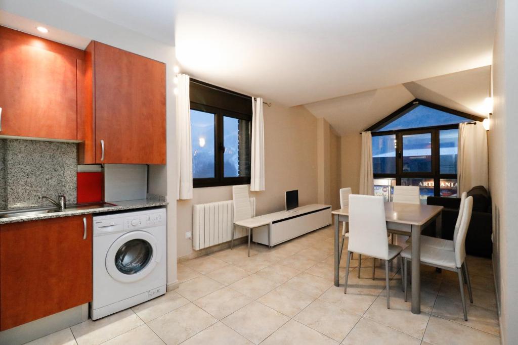 a kitchen with a washing machine and a table with chairs at Apartamentos Degas MIKKA 3000 in El Tarter