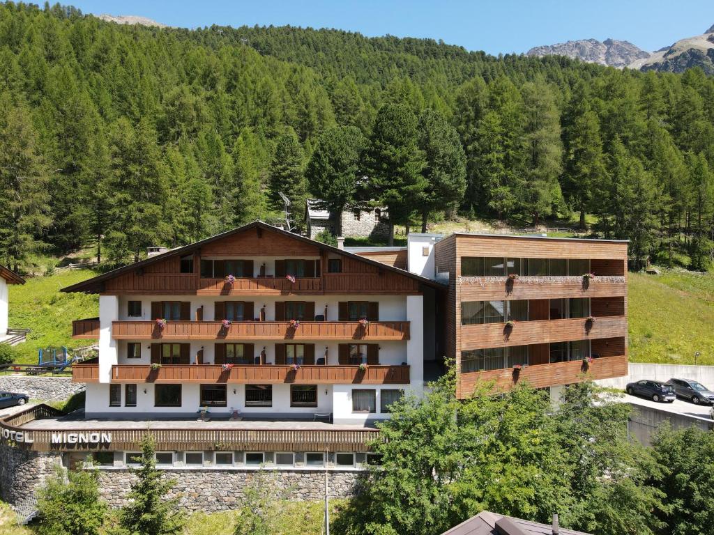 a hotel in the mountains with trees in the background at Hotel Mignon in Solda