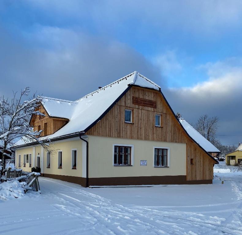 une grande maison en bois avec de la neige sur le toit dans l'établissement Penzion Stanice lyžařů Fryšava, à Nové Město na Moravě