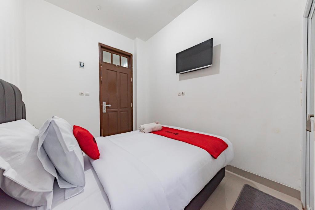 1 dormitorio con 1 cama blanca y TV en RedDoorz @ Suryakencana Bogor en Bogor
