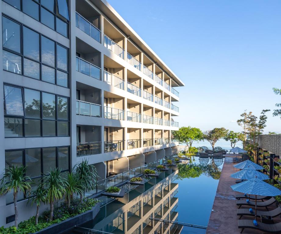 una vista exterior de un edificio con piscina y sombrillas en Golden Tulip Pattaya Beach Resort, en Norte de Pattaya