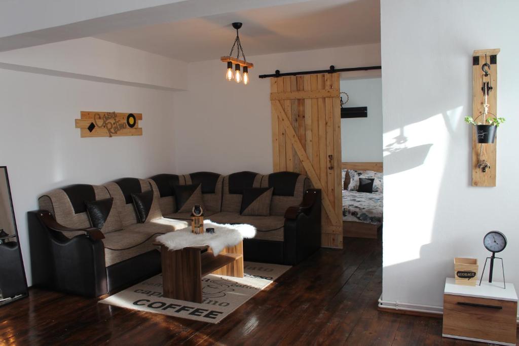 ein Wohnzimmer mit einem Sofa und einem Tisch in der Unterkunft Casa Retro Toplița in Topliţa