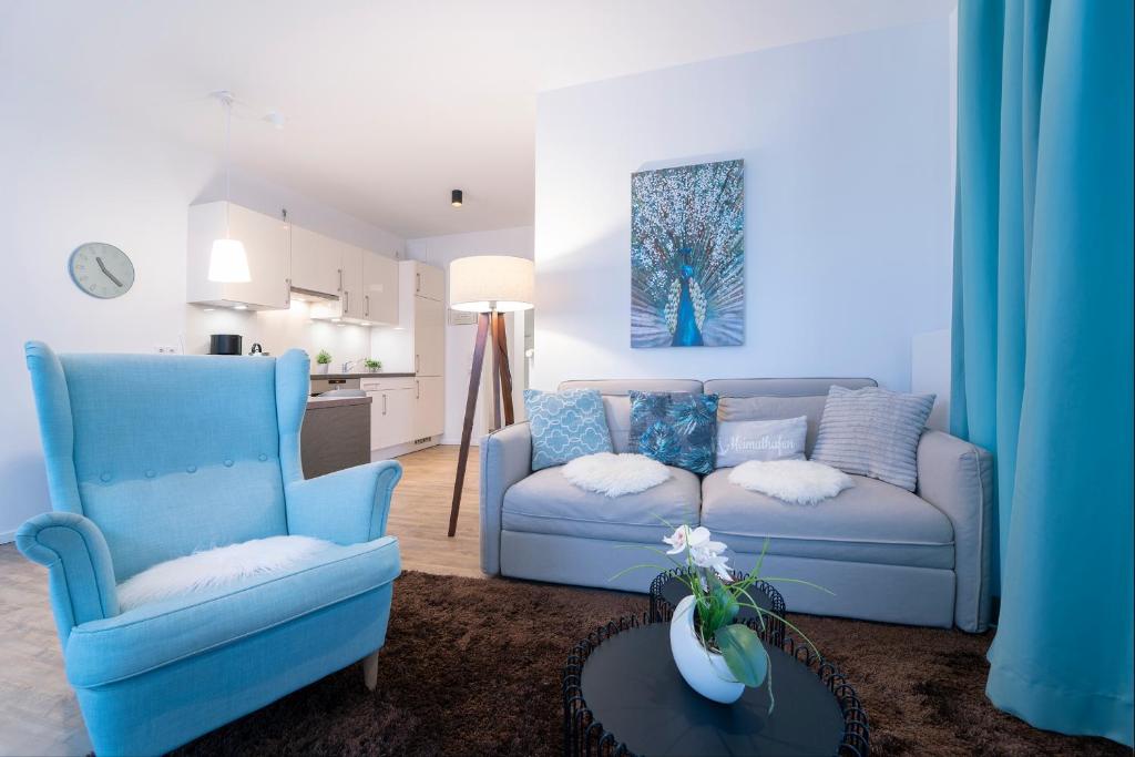 een woonkamer met twee blauwe stoelen en een bank bij KellenHus Wohnung 3 in Kellenhusen