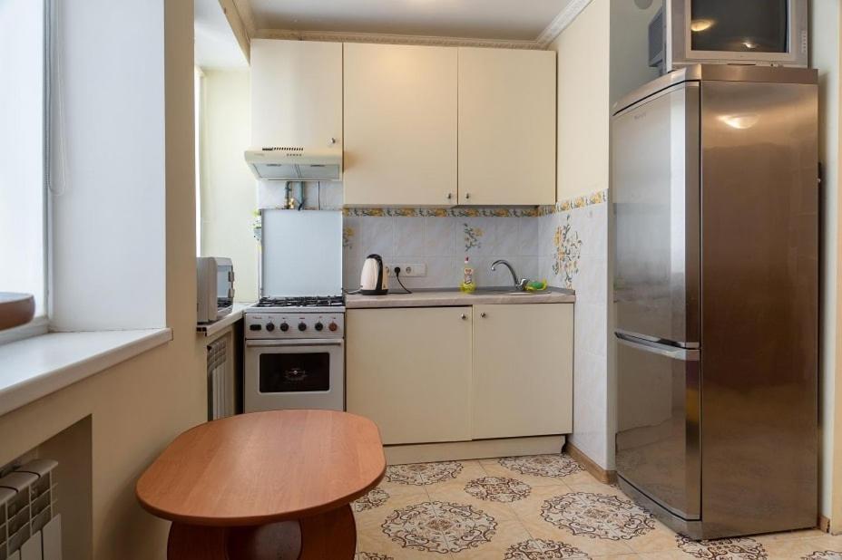 eine kleine Küche mit einem Tisch und einem Kühlschrank in der Unterkunft Khoroshaya Kvartira Goloseevskaya 3 in Kiew