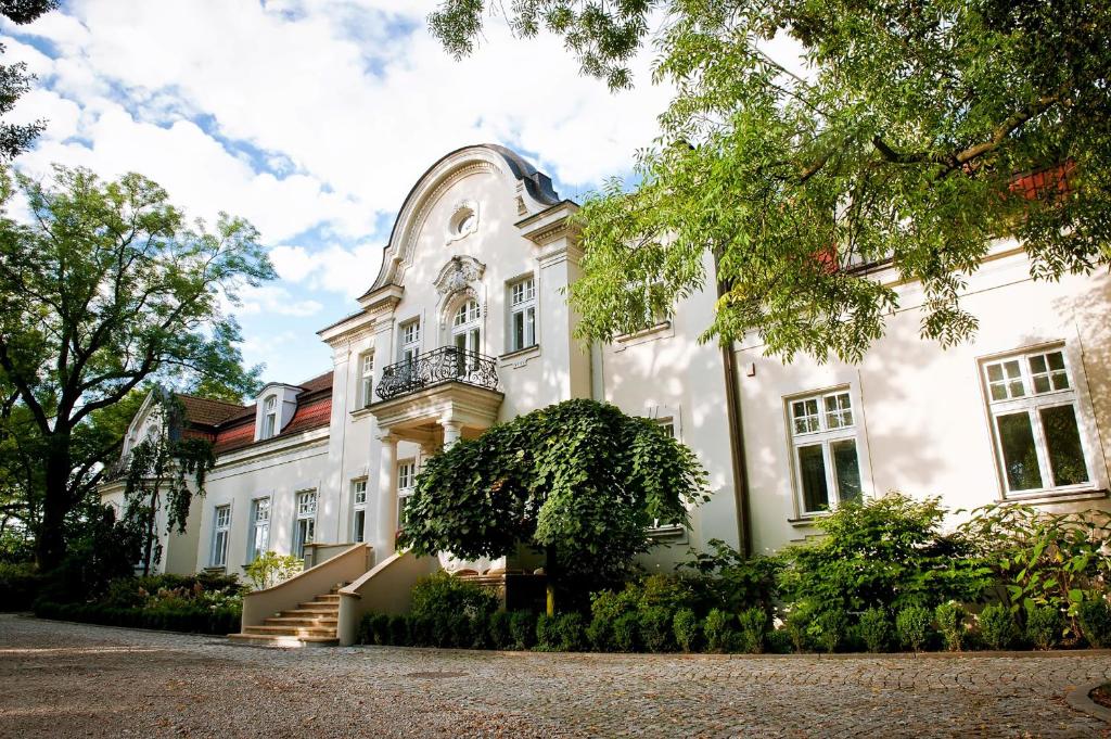 Großes weißes Gebäude mit Balkon in der Unterkunft Pałac Zdunowo in Załuski