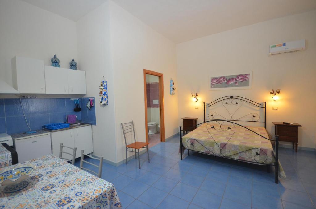 a bedroom with a bed and a table and a kitchen at Appartamenti da Clarissa in Macari