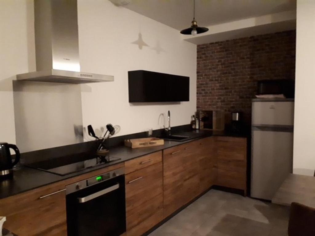 a kitchen with wooden cabinets and a black refrigerator at Appartement Mont-Dore, 3 pièces, 4 personnes - FR-1-415-77 in Le Mont-Dore