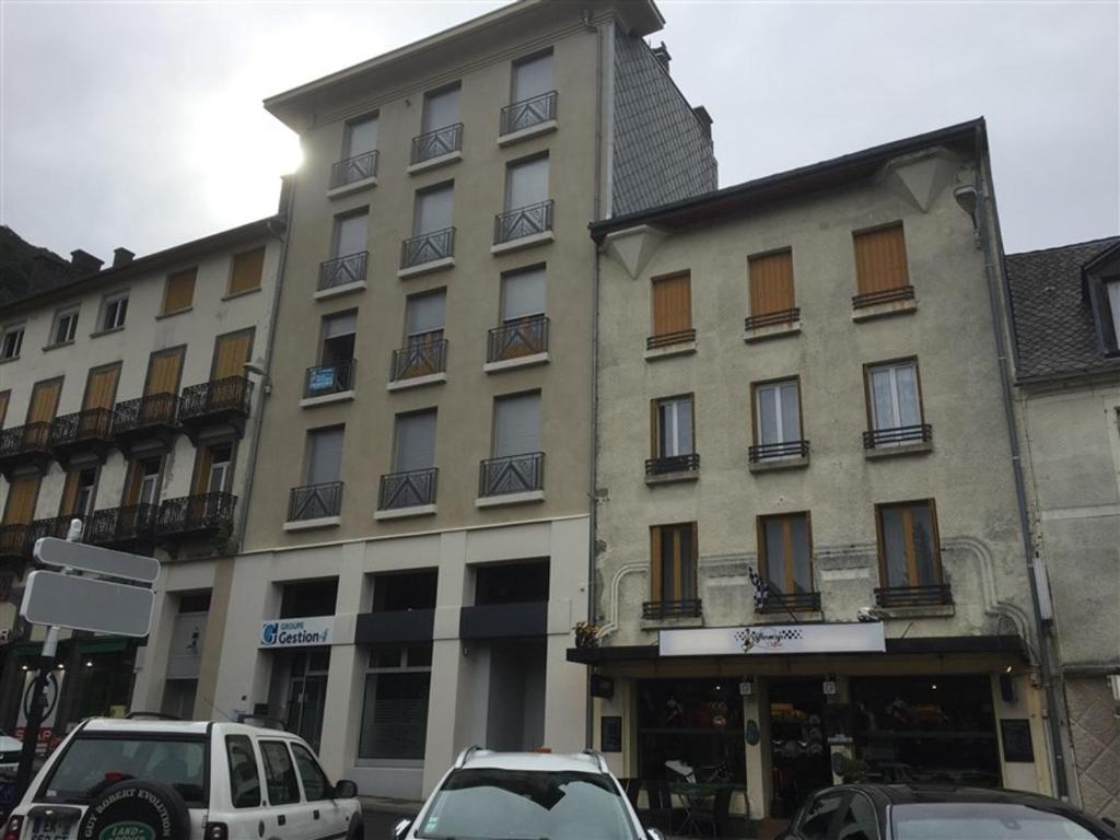 勒蒙多爾的住宿－Appartement Mont-Dore, 2 pièces, 2 personnes - FR-1-415-83，一座大型建筑,前面有汽车停放
