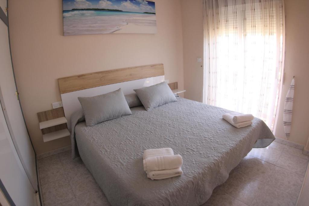 a bedroom with a large bed with two towels on it at Apartamentos Marina Internacional in Torrevieja