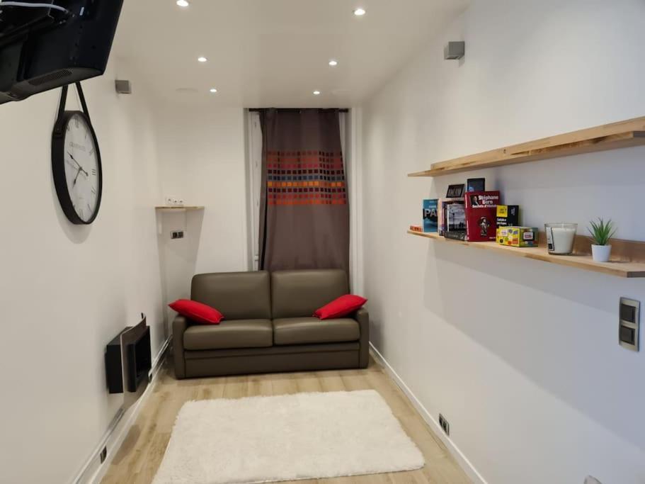 sala de estar con sofá y reloj en Suresnes : 2 pièces cosy, en Suresnes