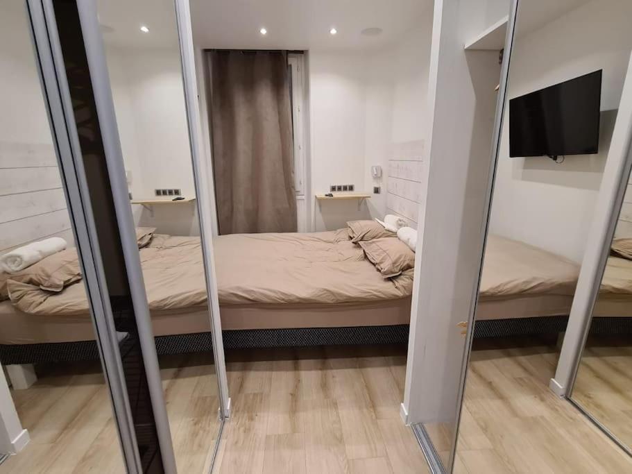 Dormitorio pequeño con cama y espejo en Suresnes : 2 pièces cosy, en Suresnes