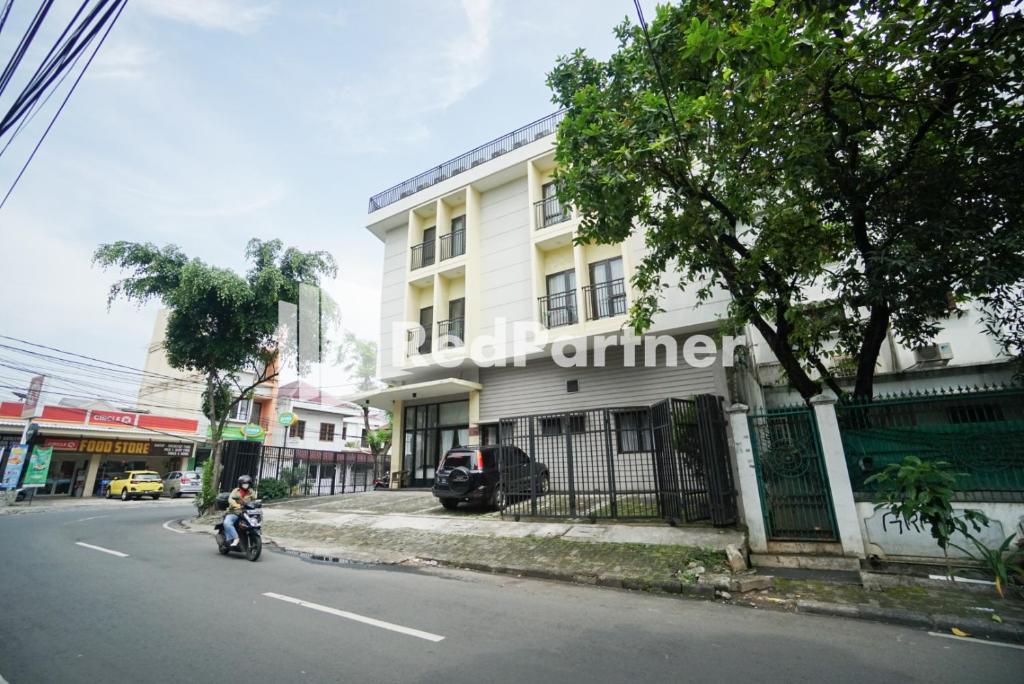 a person riding a motorcycle down a street in front of a building at Toba Mansion Syariah near Benhil RedPartner in Jakarta