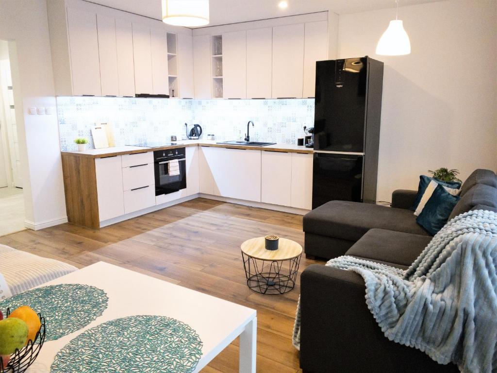 a living room with a couch and a kitchen at Apartament Skandynawski in Mielec