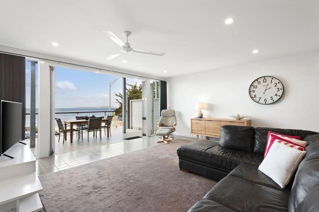 a living room with a couch and a clock on the wall at Rip n View in Point Lonsdale