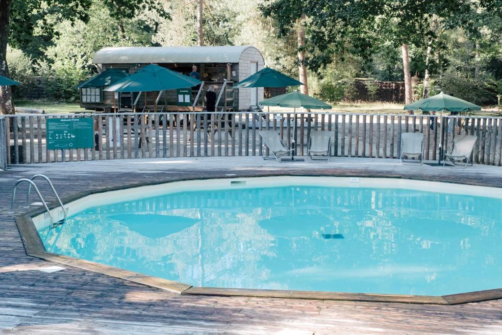 una piscina in un cortile con sedie e ombrelloni di Huttopia Lac de Sillé a Sillé-le-Guillaume